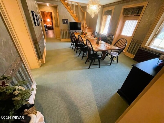 dining space with light carpet and an inviting chandelier