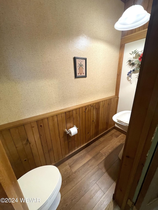 bathroom with hardwood / wood-style flooring, wood walls, and toilet