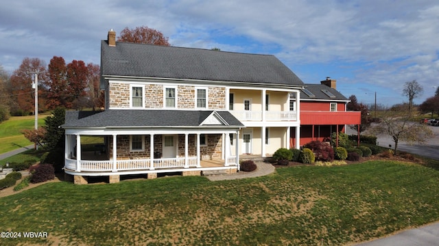 view of front of house with a front yard, a balcony, and covered porch