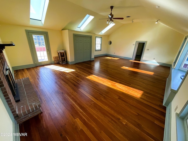 additional living space featuring lofted ceiling with skylight, a fireplace, ceiling fan, and dark hardwood / wood-style floors