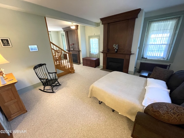 carpeted bedroom featuring radiator heating unit, a large fireplace, and multiple windows