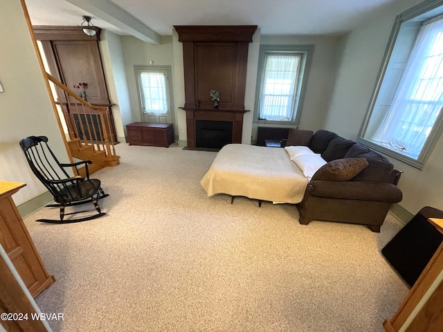 sitting room featuring beamed ceiling, carpet flooring, and a large fireplace