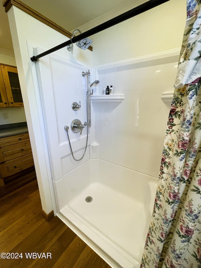 bathroom featuring wood-type flooring, a shower with curtain, and ornamental molding