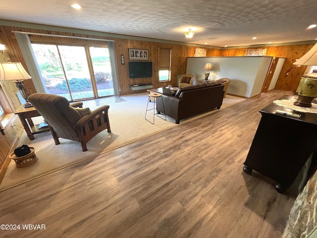 living room with hardwood / wood-style flooring, wood walls, and a textured ceiling