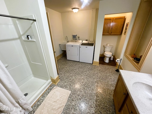 bathroom with washing machine and clothes dryer, a shower, vanity, and toilet