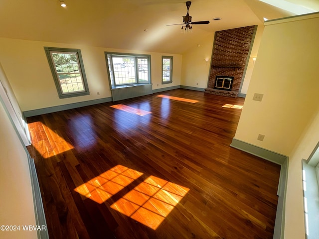 unfurnished living room with ceiling fan, dark hardwood / wood-style floors, vaulted ceiling, and a brick fireplace