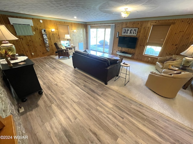 living room with wood walls, wood-type flooring, and a textured ceiling