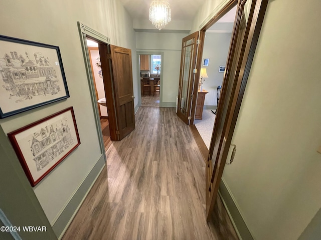 hall with hardwood / wood-style floors and an inviting chandelier