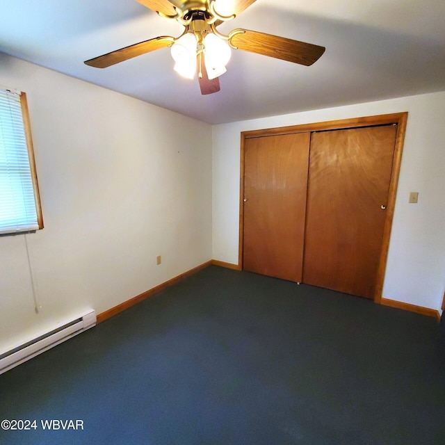 unfurnished bedroom with dark colored carpet, ceiling fan, a baseboard heating unit, and a closet