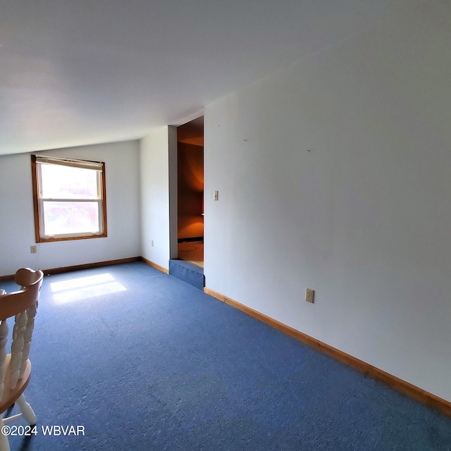 carpeted empty room featuring lofted ceiling