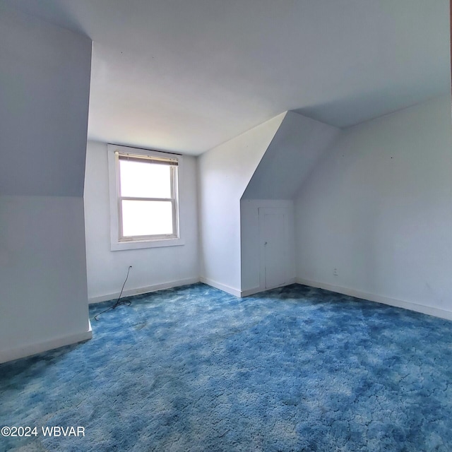 additional living space with lofted ceiling and dark colored carpet