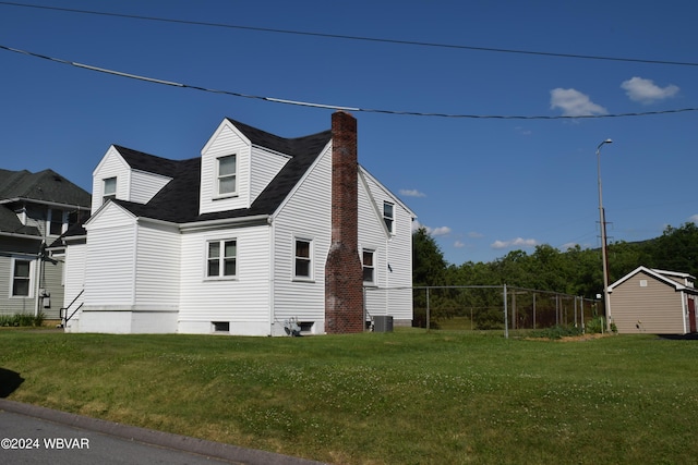 view of side of property featuring a lawn and central AC