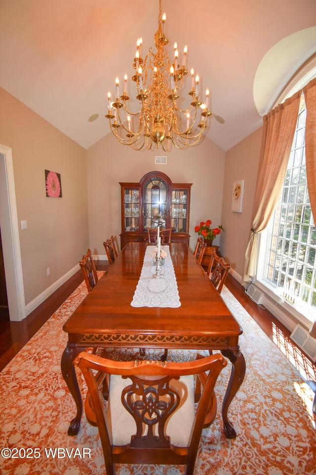 dining room featuring lofted ceiling, visible vents, wood finished floors, and an inviting chandelier