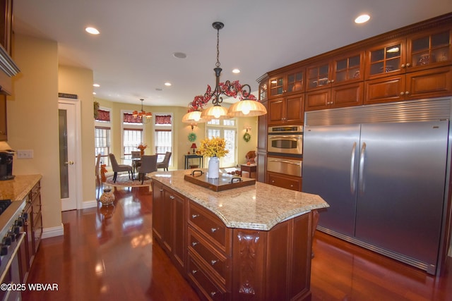 kitchen with dark wood finished floors, recessed lighting, light stone countertops, and premium appliances