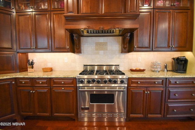 kitchen featuring reddish brown cabinets, premium range, backsplash, and custom exhaust hood