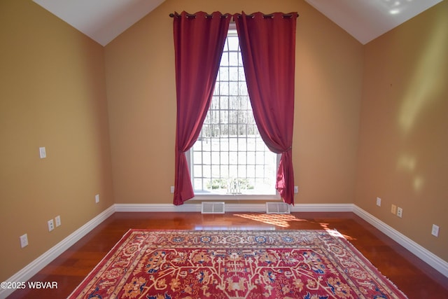spare room featuring visible vents, wood finished floors, and vaulted ceiling