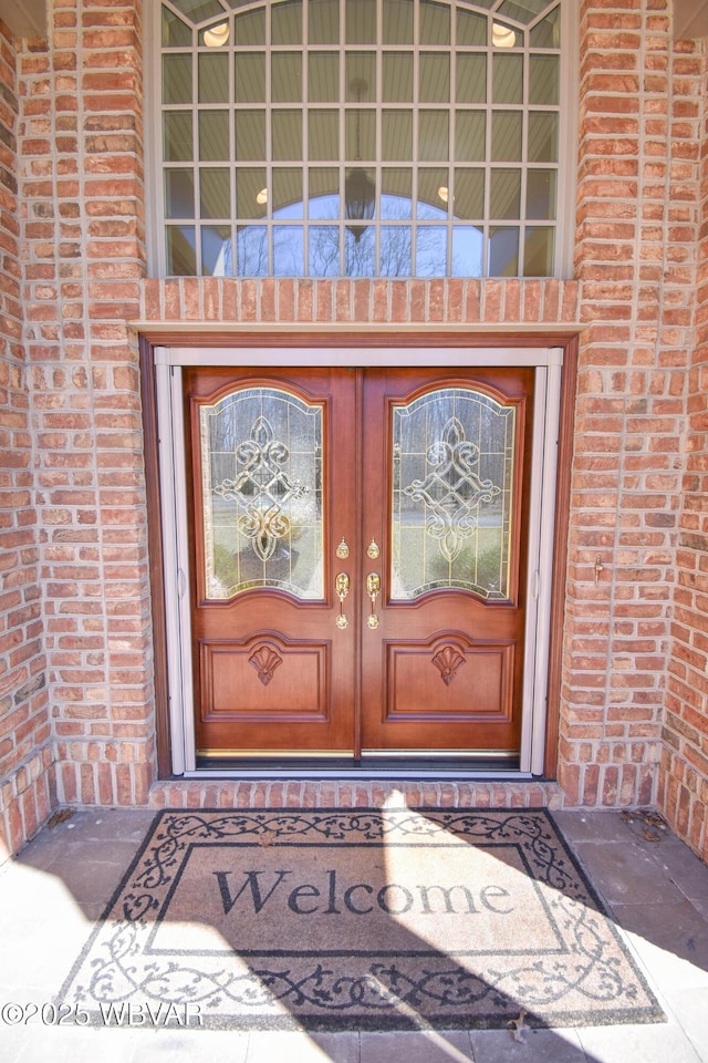 entrance to property featuring french doors and brick siding