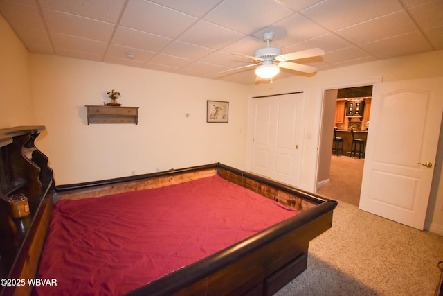 carpeted bedroom featuring a closet, ceiling fan, and a drop ceiling