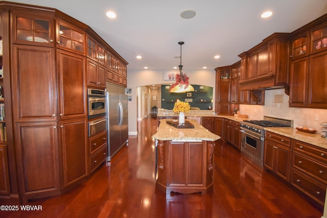 kitchen with a peninsula, stainless steel appliances, dark wood finished floors, glass insert cabinets, and backsplash