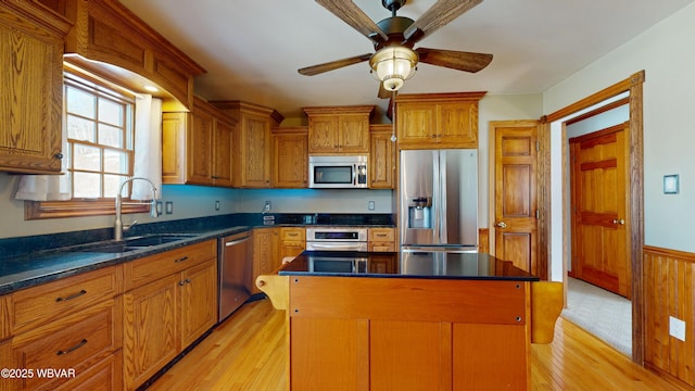 kitchen with sink, a kitchen island, ceiling fan, stainless steel appliances, and light hardwood / wood-style floors