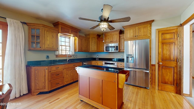 kitchen with sink, a center island, appliances with stainless steel finishes, ceiling fan, and light hardwood / wood-style floors