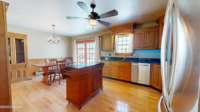 kitchen with appliances with stainless steel finishes, sink, hanging light fixtures, a center island, and light hardwood / wood-style floors