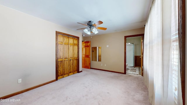 unfurnished bedroom featuring ceiling fan, light colored carpet, connected bathroom, and a closet