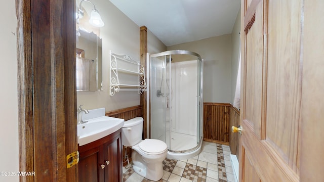 bathroom featuring walk in shower, vanity, toilet, and wood walls