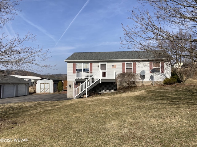 view of front facade with stairway, a front yard, roof with shingles, a storage shed, and an outbuilding