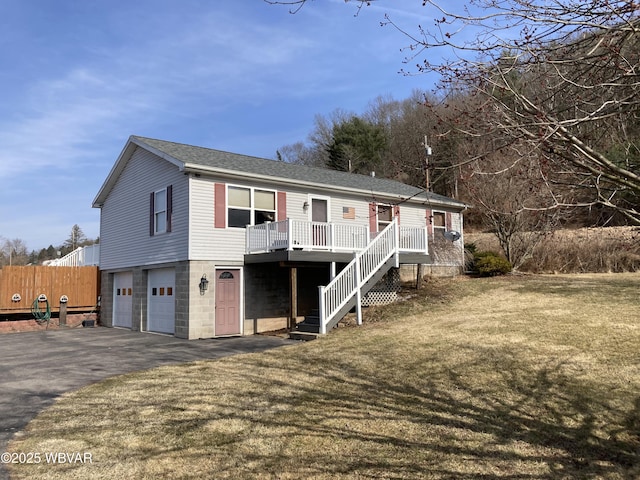 view of front of property with fence, aphalt driveway, stairway, a front yard, and a garage