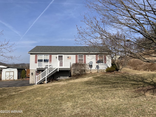 view of front of property with stairway, roof with shingles, an outdoor structure, a front lawn, and a storage unit