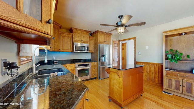 kitchen featuring sink, dark stone counters, light wood-type flooring, a kitchen island, and stainless steel appliances