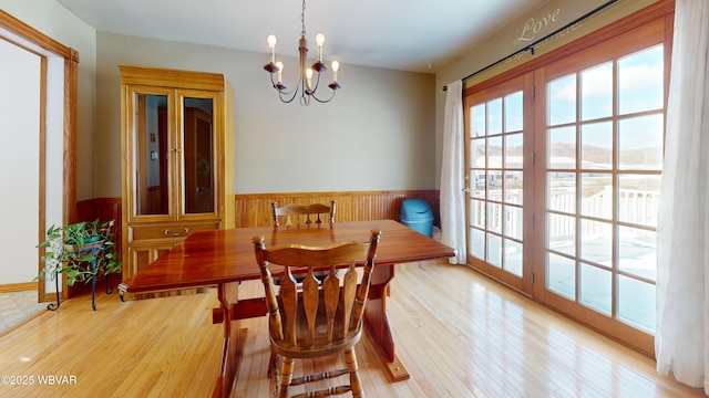 dining area with a mountain view, a notable chandelier, and light wood-type flooring