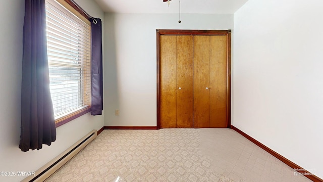 unfurnished bedroom with a baseboard radiator and a closet