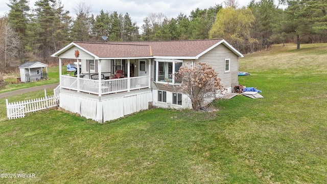 back of house with a shingled roof, fence, and a yard