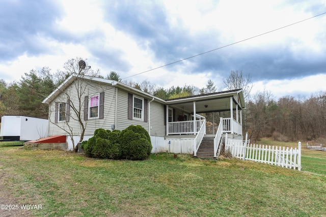 manufactured / mobile home featuring a front lawn, a porch, fence, and stairway