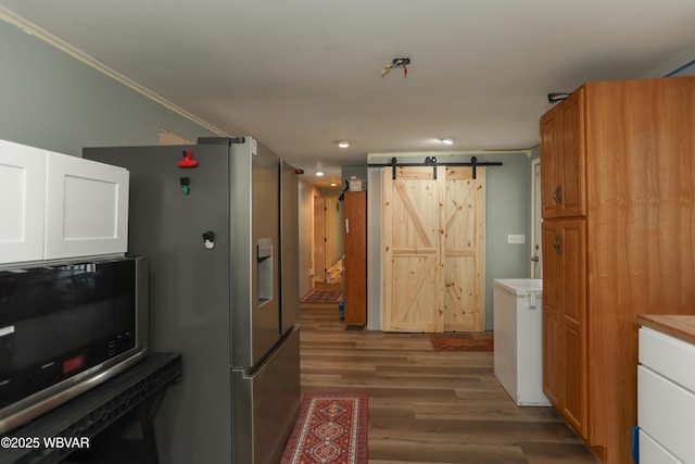 kitchen featuring a barn door, wood finished floors, light countertops, and stainless steel appliances