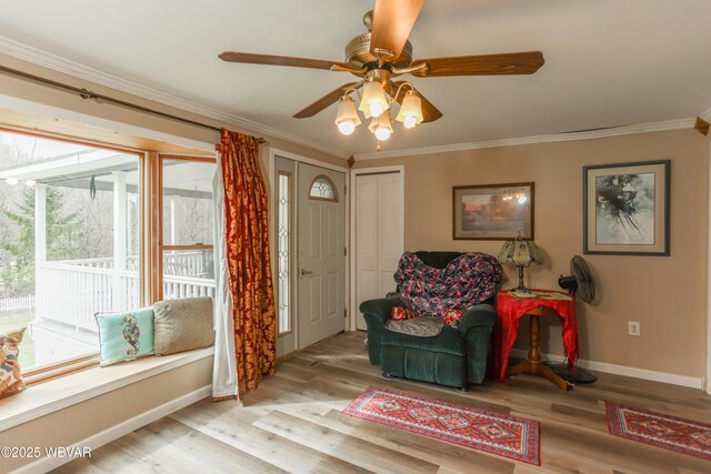 living area featuring baseboards, a ceiling fan, wood finished floors, and crown molding