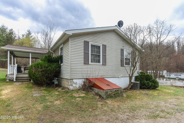 view of side of property with central AC unit, covered porch, and a yard