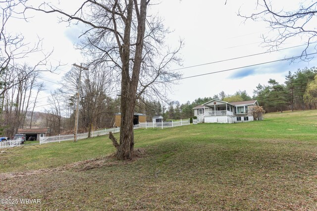 view of yard featuring an outdoor structure, a sunroom, and fence
