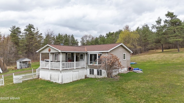 manufactured / mobile home featuring a porch, a front yard, a shingled roof, and fence