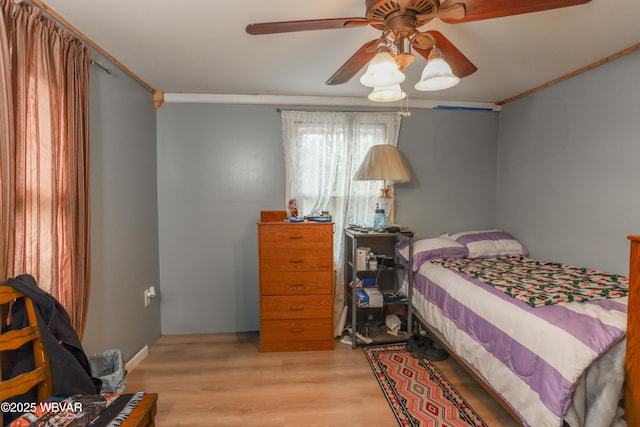 bedroom with crown molding, wood finished floors, and a ceiling fan