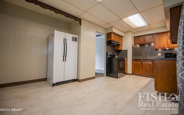 kitchen featuring backsplash, a paneled ceiling, white fridge, black / electric stove, and wood walls