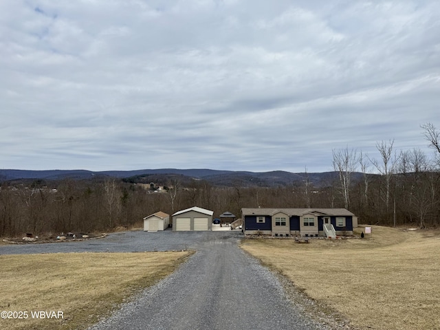 view of road with a forest view, a mountain view, and driveway