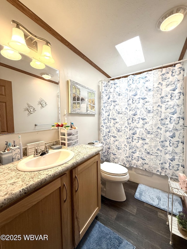 bathroom with vanity, wood finished floors, a skylight, ornamental molding, and toilet