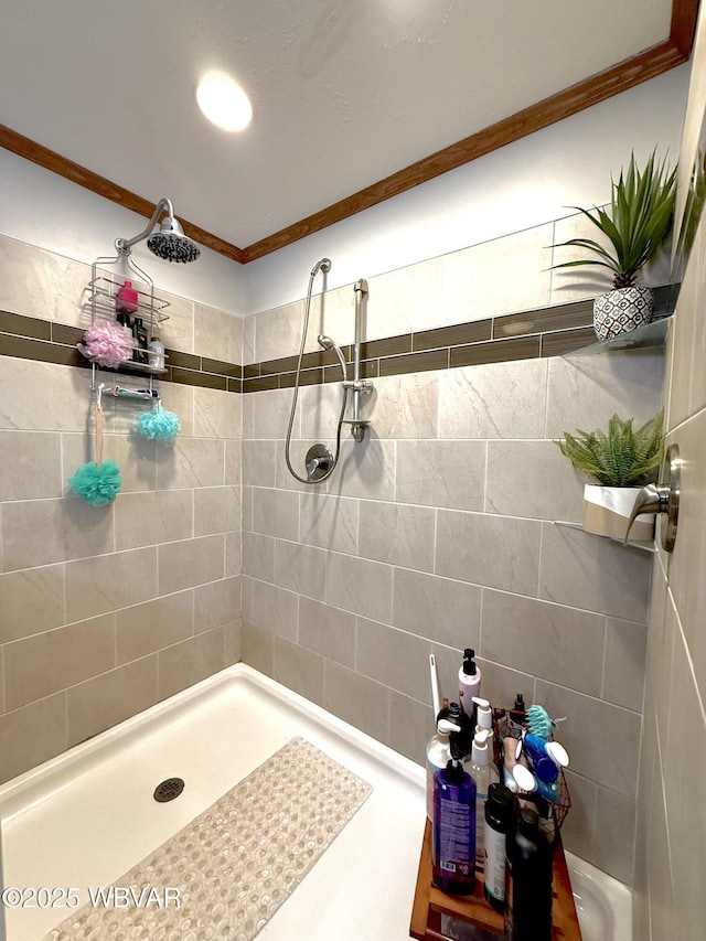 bathroom with crown molding and a tile shower