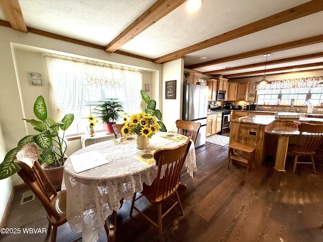 dining space with beam ceiling, visible vents, dark wood-style flooring, and a textured ceiling