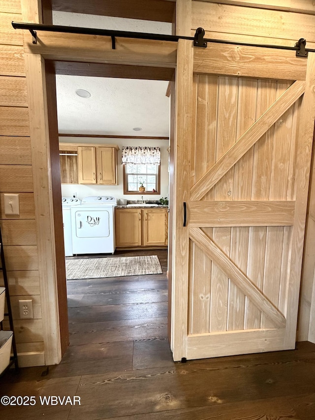 interior space with wooden walls, dark wood-style floors, light brown cabinets, separate washer and dryer, and a sink