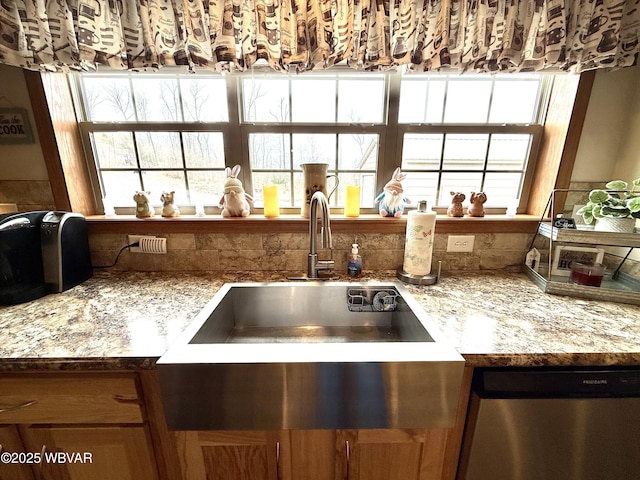 details with light stone counters, a sink, and stainless steel dishwasher