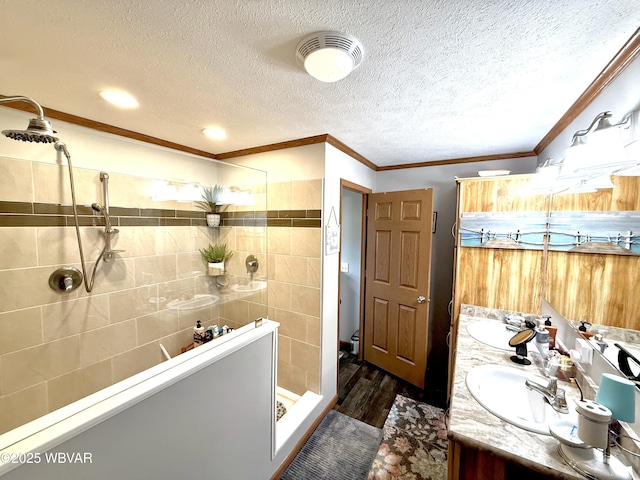 full bathroom featuring visible vents, a sink, crown molding, double vanity, and tiled shower